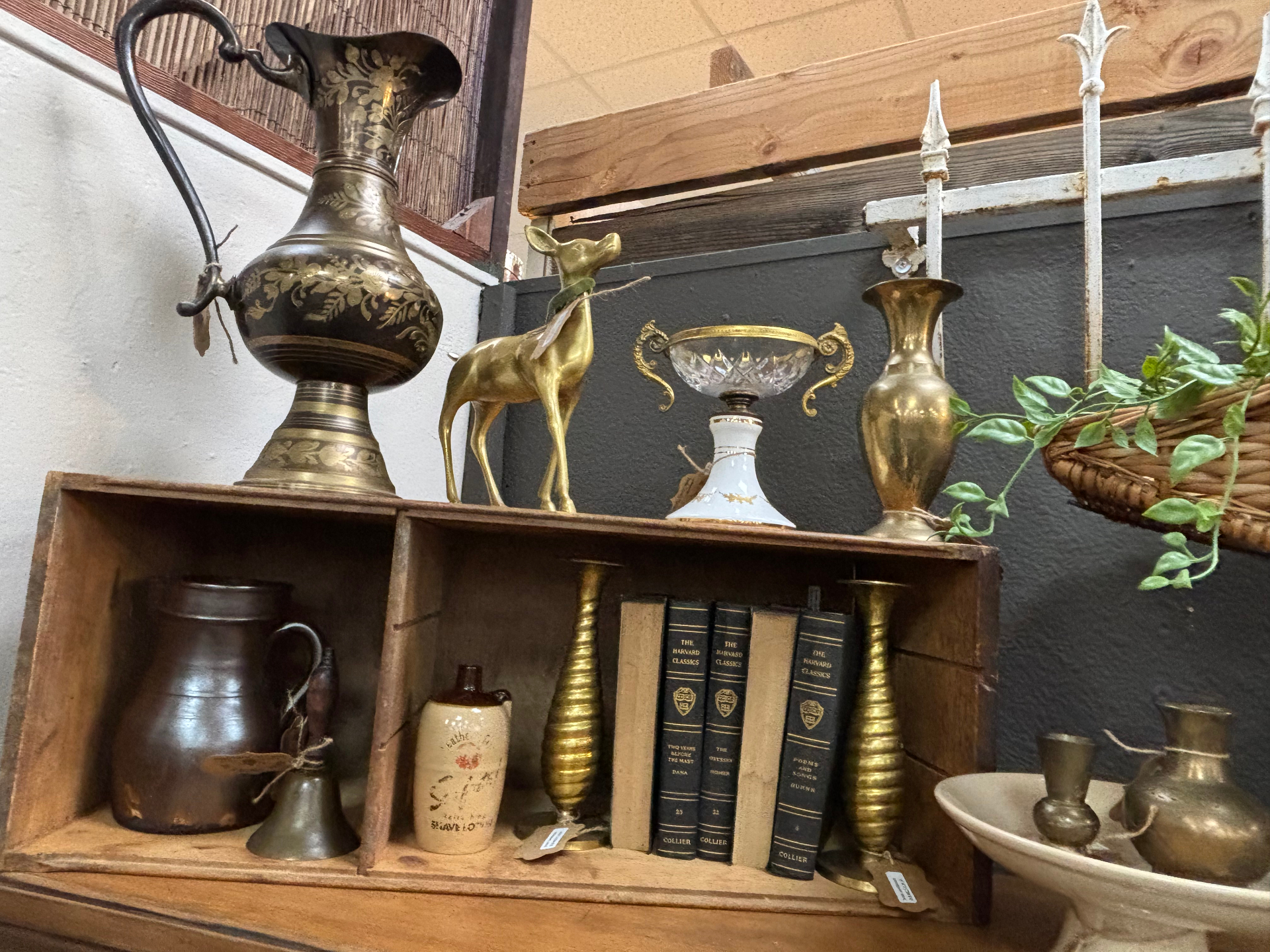 Shelf of brass vases, deer figurine, and vintage Harvard Classics books