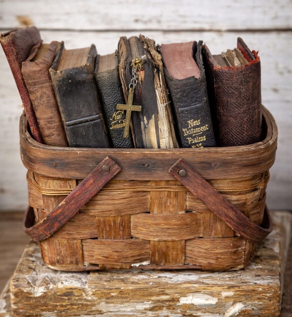 Weathered antique bibles and prayer books in a vintage woven basket